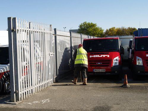 Installer fitting palisade fencing and gates at a vehicle dealership yard