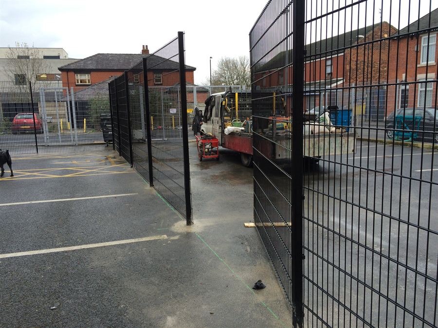 Black powder coated mesh fencing enclosing the rear service yard of a college