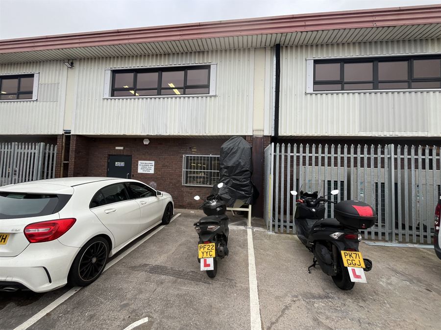 Galvanised palisade fencing along a trade unit frontage, screening air conditioning units
