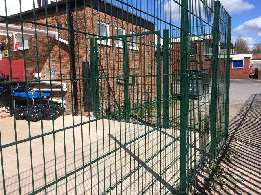 Green twin wire mesh compound at the rear of a nursery building