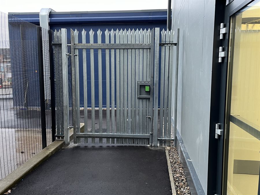 Galvanised palisade gate with access control at a building entrance