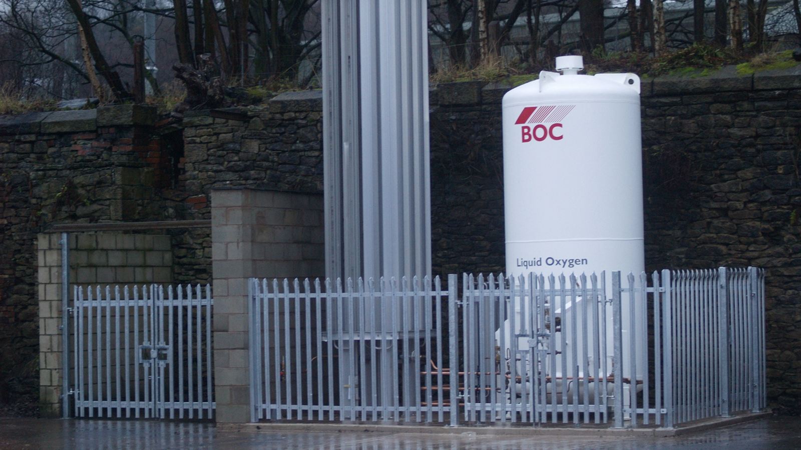 Galvanised palisade fencing securing an industrial gas storage compound