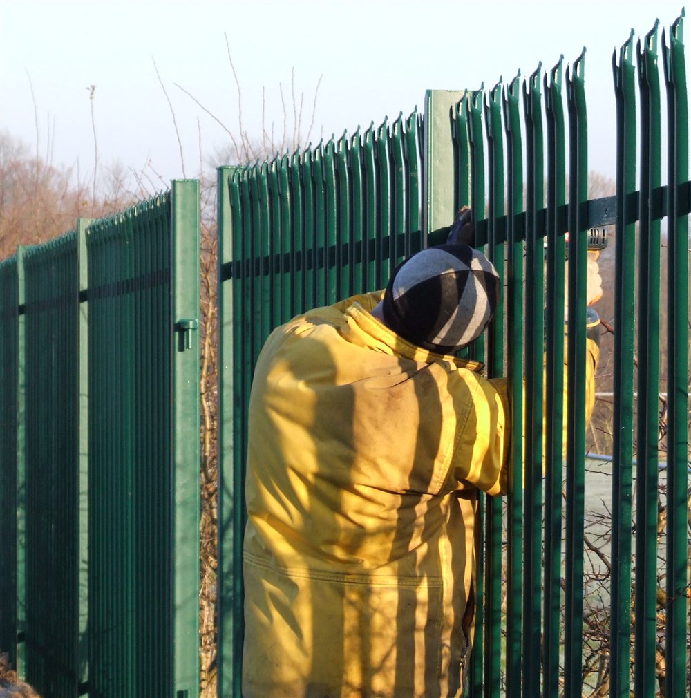 Installer fitting green palisade security fencing